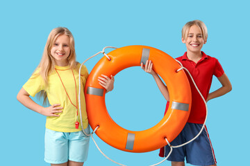 Happy little children lifeguards with ring buoy on blue background