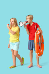 Little children lifeguards with ring buoy and megaphone whistling on blue background