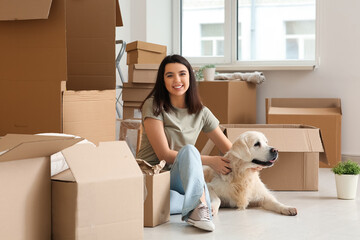Fototapeta premium Young happy woman and cute Labrador dog with boxes on moving day sitting at home