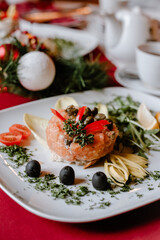Salmon tartare with olives and tomatoes on Christmas table.