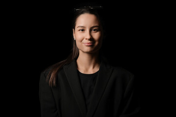 Portrait of pretty young woman in black clothes on dark background