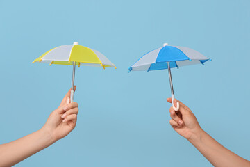 Female hands with different mini umbrellas on blue background