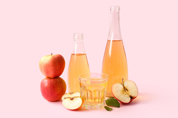 Composition with bottles and glass of fresh apple cider on pink background