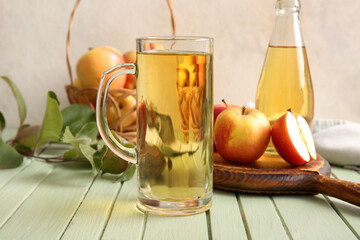 Composition with fruits, wooden tray and glass of fresh apple cider on green wooden table, closeup