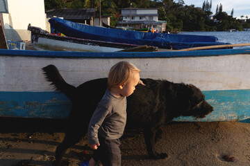 A young boy and his loyal dog walk together by the seaside, sharing a peaceful moment