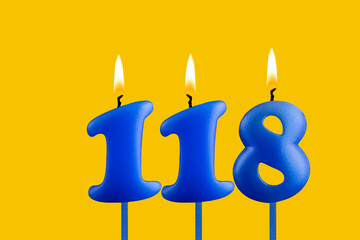 Blue birthday candle on yellow background - Number 118