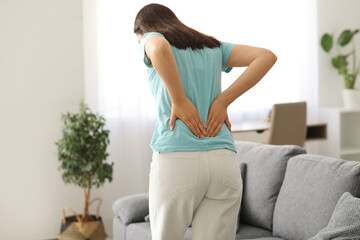 Young woman suffering from back pain at home