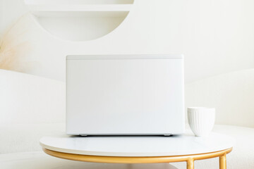 Gray laptop stands on table in white room front view.