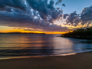 Sunrise over the ocean with clouds and a calm sea