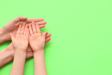 Female and child's hands on green background