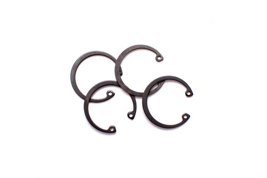 Black circlip retaining rings scattered on a white background.