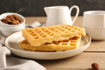 Plate with tasty Belgian waffles, almond and cup of coffee on wooden table
