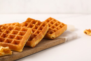 Board with tasty Belgian waffles on white background