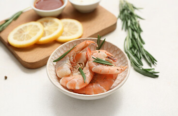 Bowl with tasty boiled shrimps, rosemary and lemon on white background