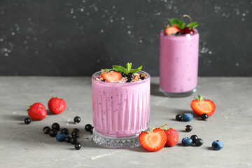 Glasses of fresh smoothie with different berries and mint on grey table
