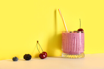 Glass of fresh smoothie with different berries on colorful background