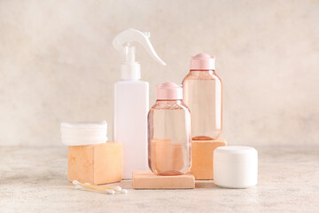 Bottles of micellar water, plaster stands and cotton pads on beige grunge background