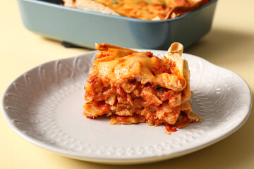 Plate with piece of tasty enchilada on color background, closeup