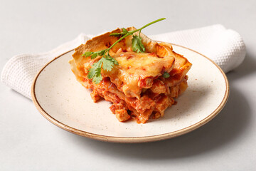 Plate with piece of tasty enchilada and napkin on light background