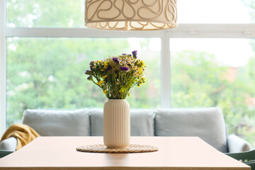 Vase with wildflowers on dining table in room