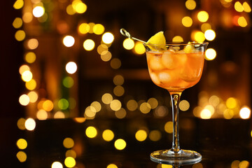 Glass of Aperol spritz cocktail on table against blurred lights