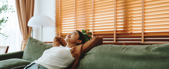 Relaxed young Asian woman enjoying rest on comfortable sofa, calm attractive girl relaxing on...