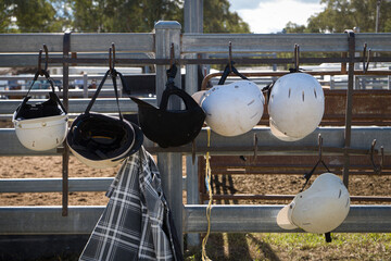 Hourse riding helmets hanging on the fence