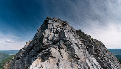 Fototapeta premium at the tip of a tall, steep black rock mountain, offering dramatic views from above. generatrive ai