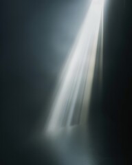 A single ray of light pierces through a dark, misty room