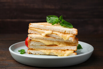Pieces of toasted bread with melted cheese and basil on wooden table