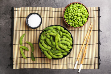 Raw green edamame soybeans and pods on grey table, top view