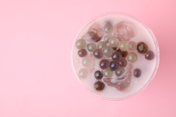 Tasty milk bubble tea in plastic cup on pink background, top view. Space for text