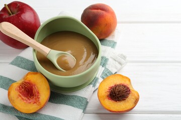 Delicious baby food in bowl and ingredients on white wooden table, closeup