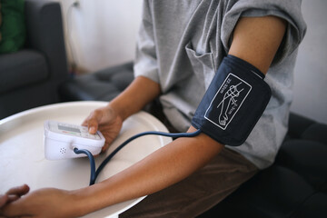 Close Up Of Hands Medical Checking At Home Using Blood Pressure Test