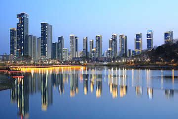 Sejong-si, Chungcheongnam-do, South Korea - April 9, 2022: Sunset and night view of apartments with light and reflection on water at Sejong Lake Park in spring