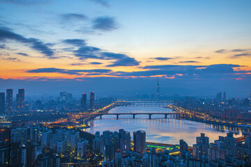 Seongdong-gu, Seoul, South Korea - February 2, 2022: Aerial and dawn view of Han River with bridges and apartments against Lotte World Tower in the background