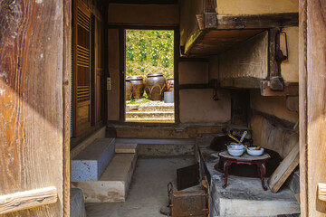 House of Yu Gi-bang, Seosan-si, Chungcheongnam-do, South Korea - April 6, 2022: Interior of entrance door and kitchen of Hanok(traditional Korean-style house) against crocks and daffodil flowers