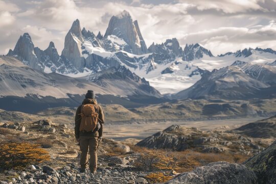 A person with a backpack standing at the base of a mountain, ready for an adventure