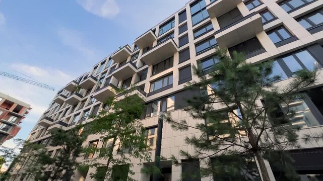 Upward Gaze at Urban Elegance: Low-Rise Luxury Complex Against Open Sky | Stone and Glass Facade from Ground-Level Perspective | Innovative Architecture Revealed in Sweeping Camera Move