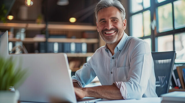 Smiling mature business executive using laptop in office professional corporate technology manager working at desk