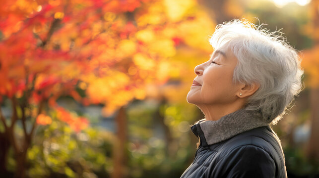 Japanese elderly woman breathing a fresh air in the park, meditation