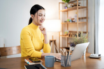 Young attractive woman working on her project with laptop computer in modern home office room.