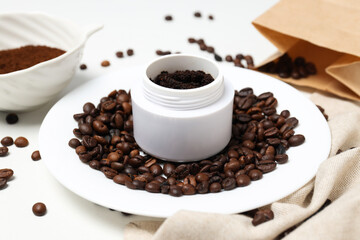Coffee body scrub, in a container with whole coffee beans, on a white background.