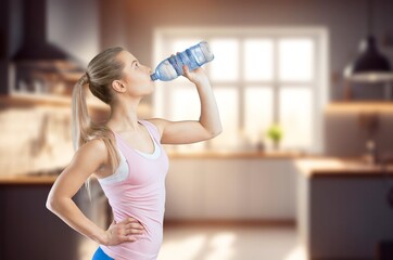 A young pretty woman drinking water at kitchen