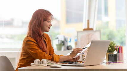 Smiling creative woman working with laptop computer in office.