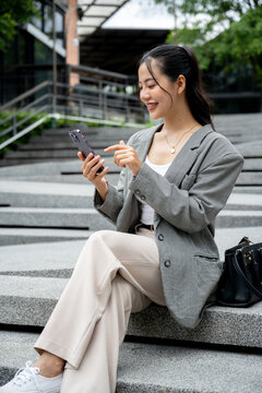 Asian businesswoman reading messages or replying to chats on her smartphone