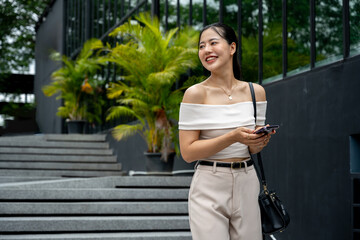 Asian woman in a trendy outfit replying to a chat or using a mobile app.