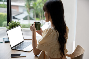 Asian woman working on her laptop in a modern coffee shop