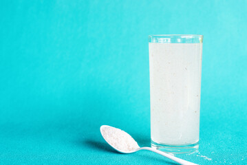 A glass of water soluble psyllium husk dietary fiber supplement on light aqua  background.