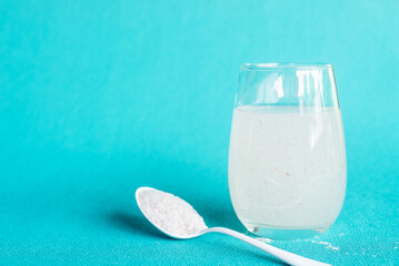 A glass of water soluble psyllium husk dietary fiber supplement on light aqua  background.